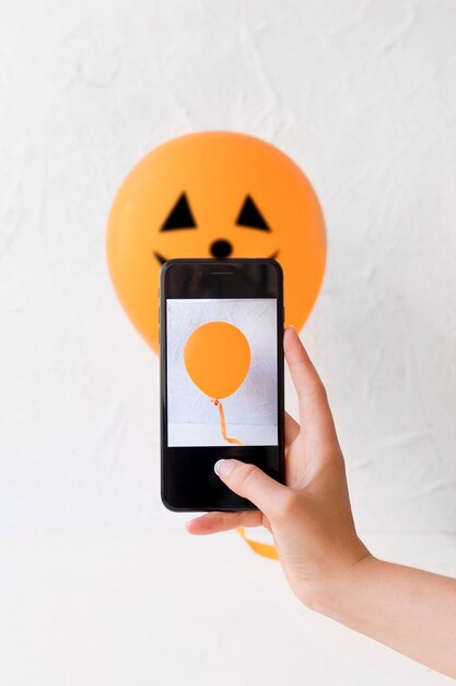 ハロウィーンの風船の近くでスマートフォンで手作り