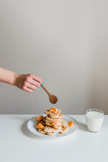 Crop hand with spoon over waffles