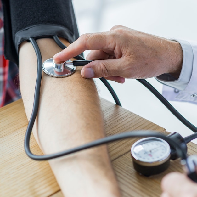 Crop hand with stethoscope measuring blood pressure