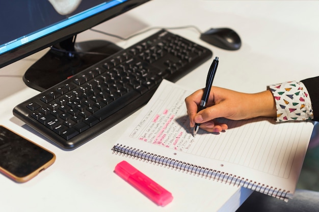 Foto gratuita ritaglia la scrittura a mano nel notebook vicino al computer