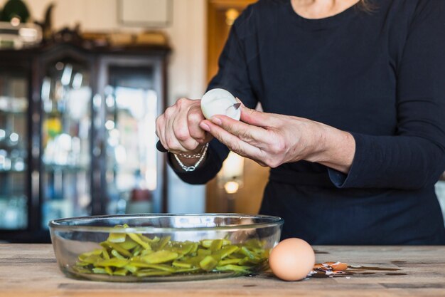 Crop hands of aged woman cooking tasty dish in kitchen