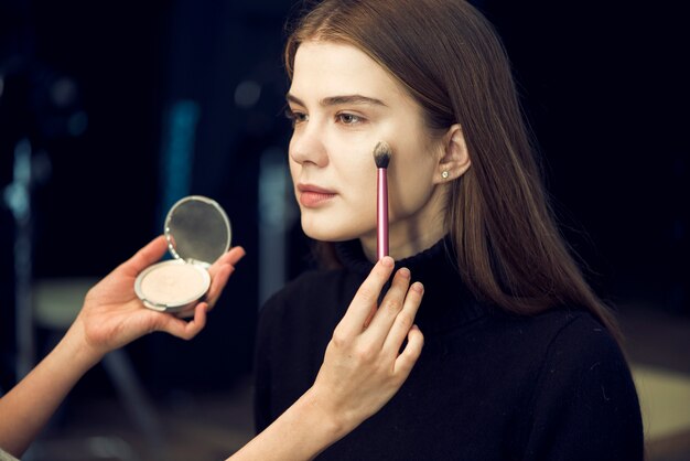 Crop hands applying powder on lovely model