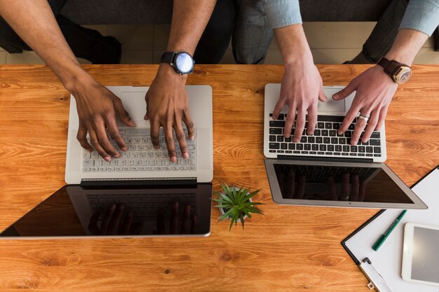 Crop hands browsing laptops