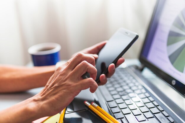 Crop hands browsing smartphone in office