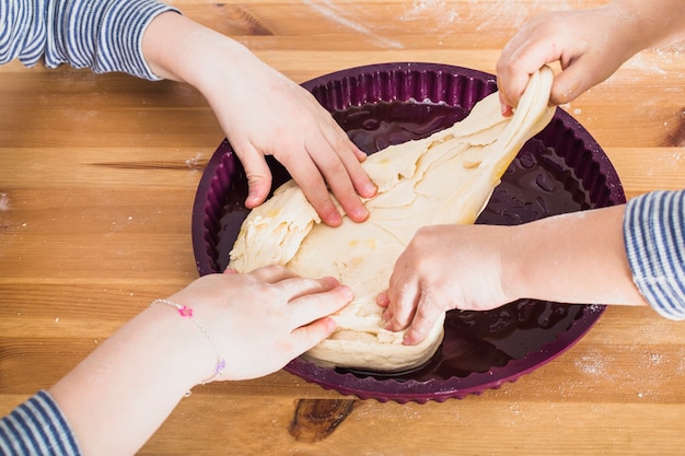 Crop hands of children putting dough in mold