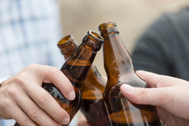 Crop hands clinking beer bottles
