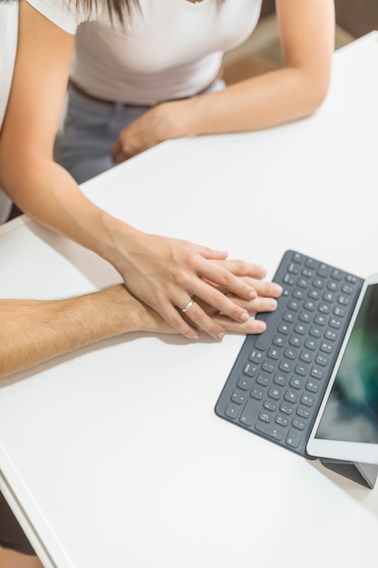 Crop hands of couple near tablet