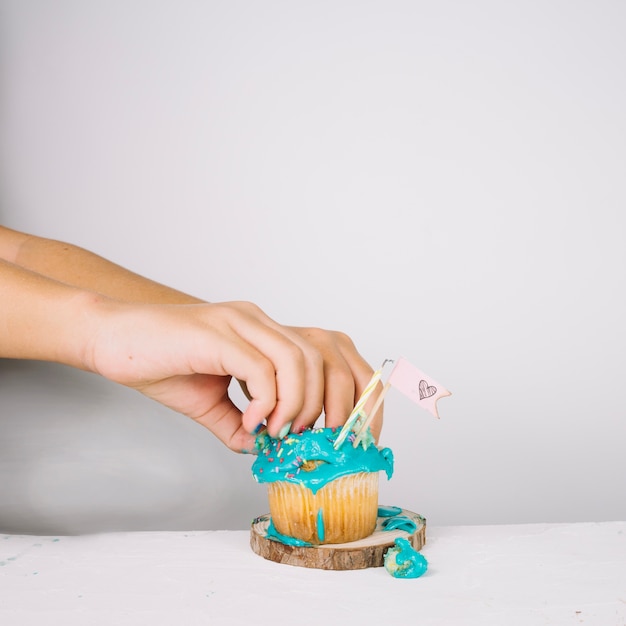 Crop hands crushing cupcake
