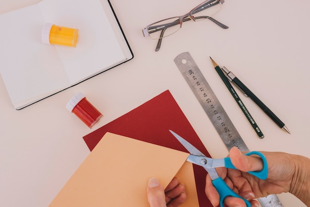 Foto gratuita ritaglia le mani tagliando la carta del mestiere