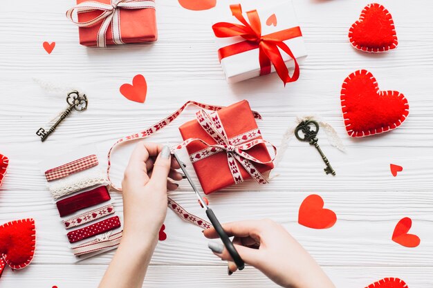 Crop hands cutting ribbon on gift box