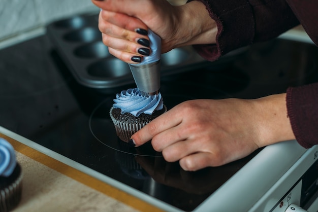 Crop hands decorating cupcake