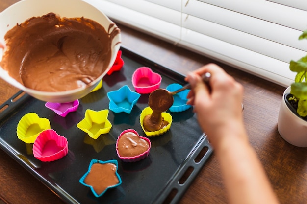 Crop hands filling cups with batter