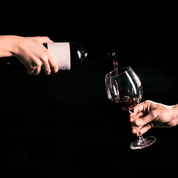 Crop hands filling glass with wine