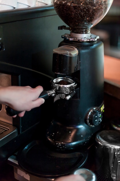 Crop hands grinding coffee into portafilter