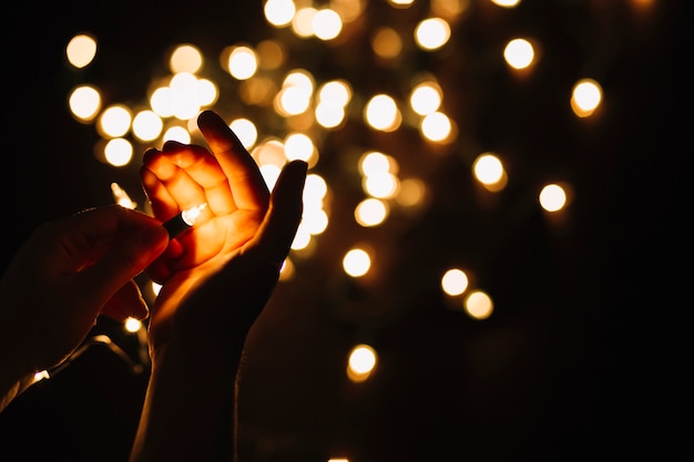 Foto gratuita ritaglia le mani tenendo la lampadina della ghirlanda