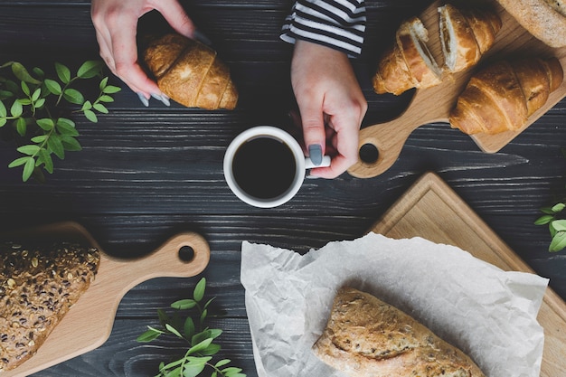 Crop hands holding coffee and croissant