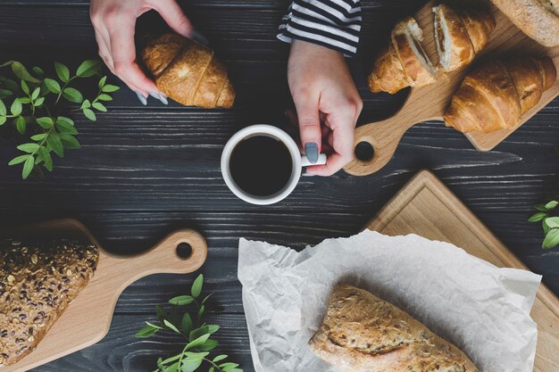 Crop hands holding coffee and croissant