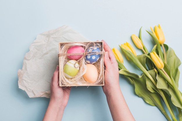 Free photo crop hands holding eggs near tulips