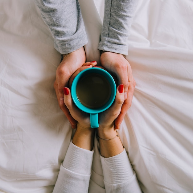 Crop hands holding mug with hot beverage