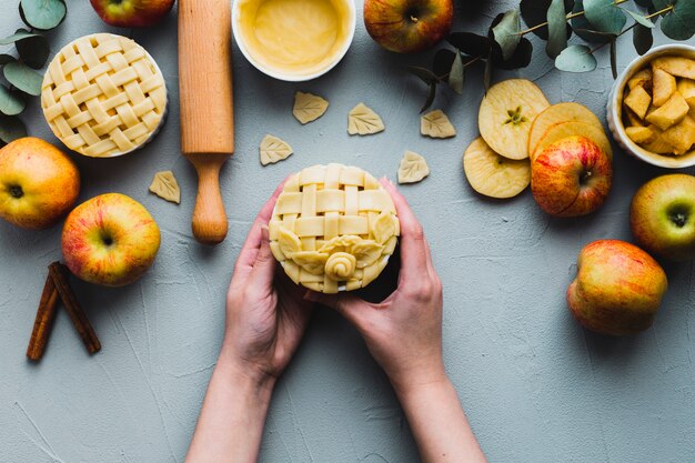 Crop hands holding pie near apples