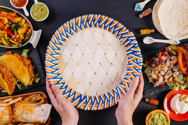 Crop hands holding plate near Mexican food