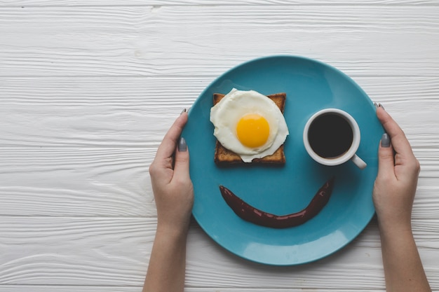 Foto gratuita ritaglia le mani tenendo il piatto con la colazione