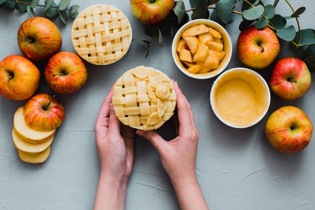 Crop hands holding raw pie near apples