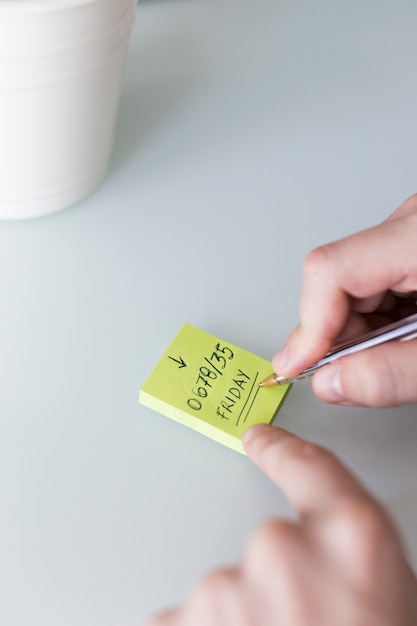 Crop hands leaving information on sticky note