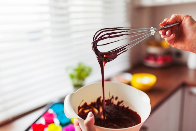 Crop hands mixing batter with whisk