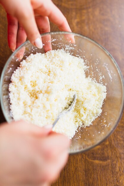 Crop hands mixing shredded coconut