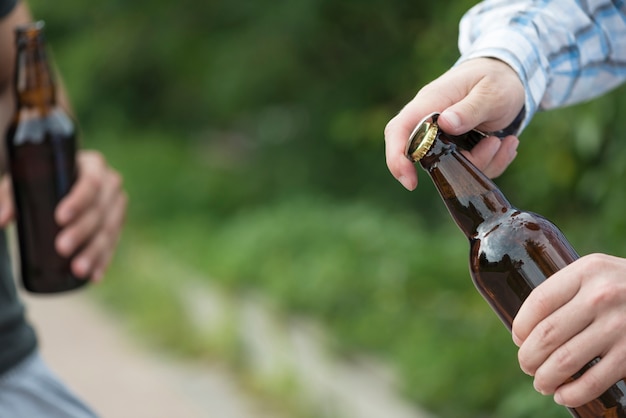 Crop hands opening beer near friend