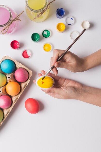 Foto gratuita ritaglia le mani dipingendo sull'uovo