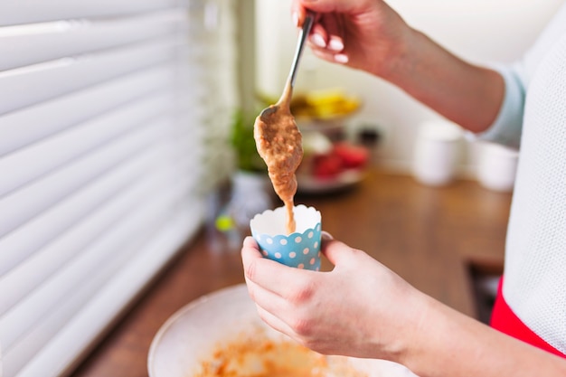 Crop hands pouring batter into cup