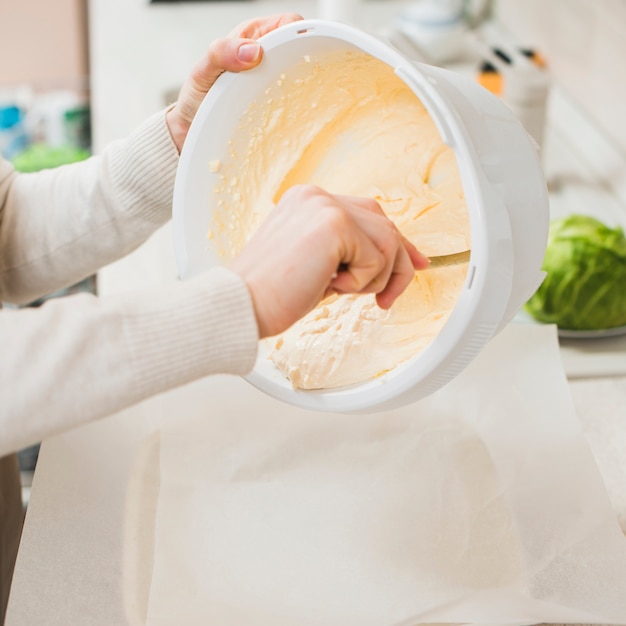 Crop hands putting batter into ceramic pan