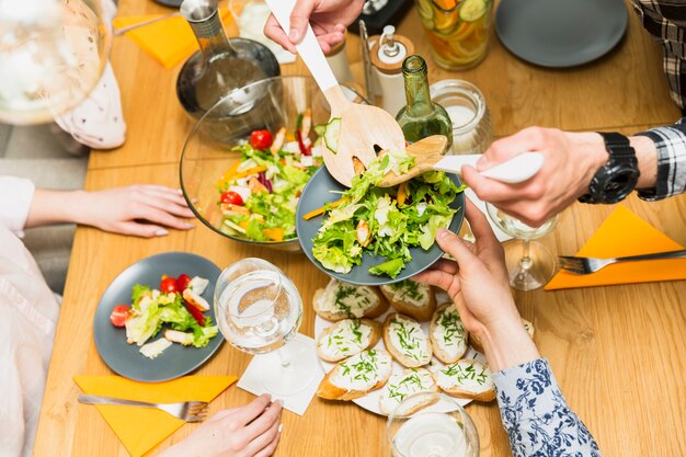 Crop hands putting delicious salad on plate