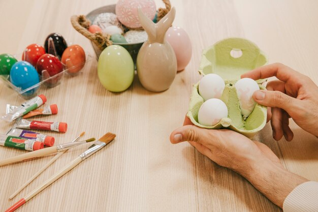 Crop hands putting eggs into carton