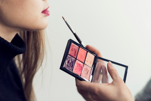 Crop hands rouging lipsof young woman