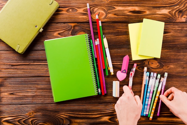 Free photo crop hands sorting pens near notebooks