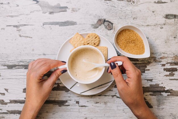 Crop hands stirring sugar in coffee