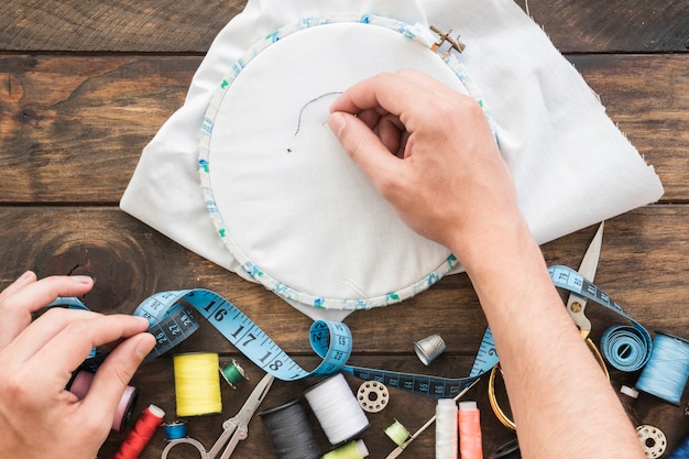 Crop hands stitching near sewing supplies