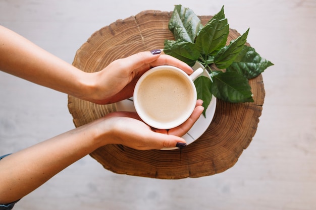 Crop hands taking coffee cup from saucer