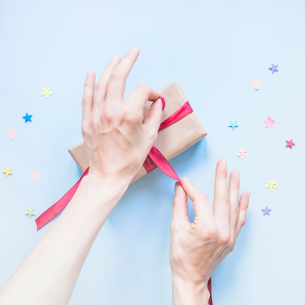 Crop hands tying ribbon on present