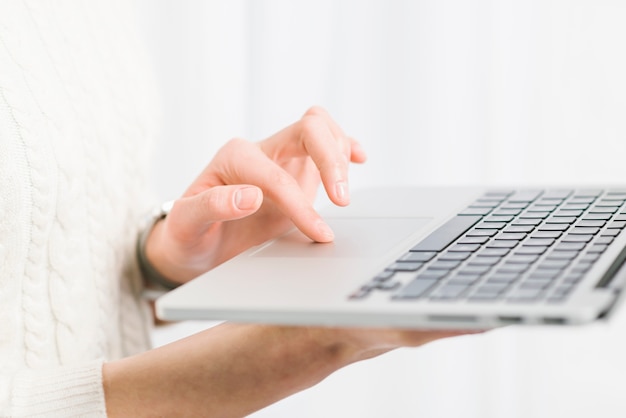 Crop hands using laptop near window