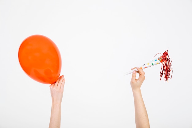 Foto gratuita ritaglia le mani con palloncino e corno da festa