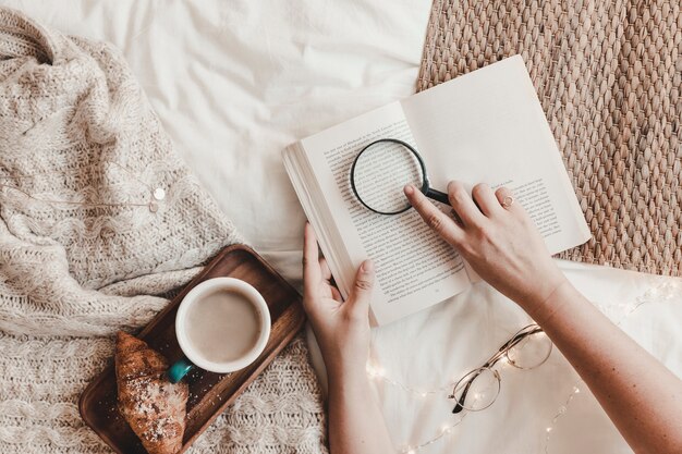 Crop hands with book near breakfast food