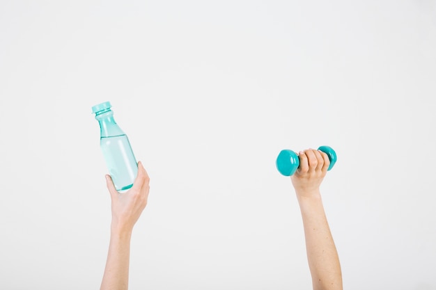 Crop hands with bottle and dumbbell