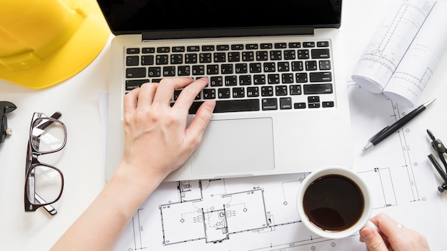 Crop hands with cup of coffee browsing laptop