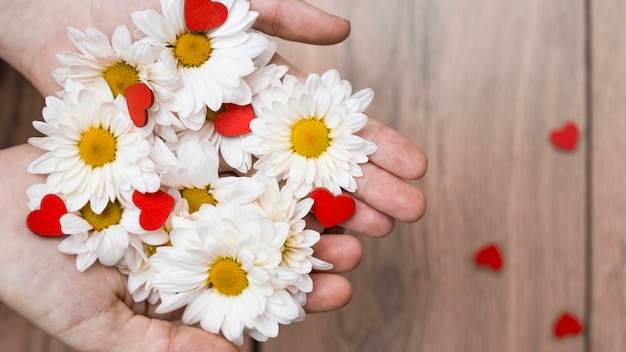 Foto gratuita ritaglia le mani con un mucchio di fiori e cuori