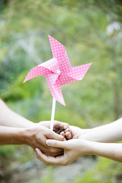 Free photo crop hands with soil and paper windmill