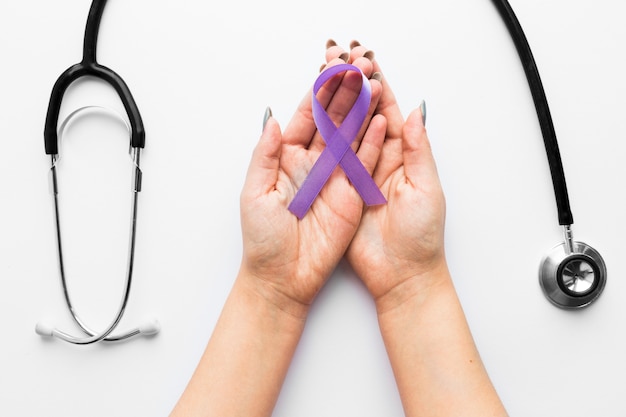 Crop hands with violet ribbon near stethoscope